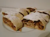 Kilka kawałków pysznego strudla z jabłkami, posypanych cukrem pudrem, czeka na talerzu.