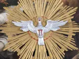 Ein silberner Taube mit ausgebreiteten Flügeln vor einem goldenen Strahlenkranz. Dies symbolisiert den Heiligen Geist und was bedeutet Pfingsten: die Ausgießung des Geistes.