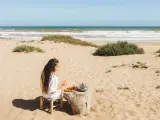 Kobieta pije herbatę na plaży, delektując się widokiem na wzburzone morze. To właśnie takie morze można podziwiać w Tunezji.