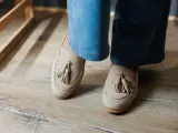 Beżowe mokasyny z frędzlami na drewnianej podłodze. Urocze stupki w casualowym stylu.