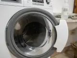 Dettaglio di una lavatrice con oblò aperto, pronto per un ciclo di pulizia con aceto bianco, per una vita media ottimale dell'elettrodomestico.