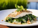 Filet ryby, czy to halibut, czy sandacz, podany na szpinaku z orzechami i bazylią.