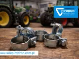 Metalowe opaski zaciskowe, czyli trytytki, na drewnianym blacie. W tle zielone traktory i logo Hydron.