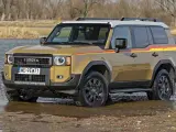 Złoty Toyota Land Cruiser Prado z kolorowymi pasami na boku, wjeżdża do wody.