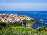 Malownicze miasteczko na wybrzeżu Portugalii, z białymi domami i pomarańczowymi dachami, nad błękitnym oceanem. Ceny wakacji w Portugalii mogą być zaskakująco przystępne.