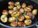 Gegrillte Rosmarinkartoffeln mit grobem Salz und Kräutern auf einem Rost.