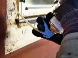 Person med handske applicerar lågexpanderande fogskum i en springa i trä.