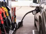 Tankowanie samochodu na stacji paliw. Wąż z pistoletem wlewu paliwa podłączony do baku. Warto docenić obniżki cen paliw.