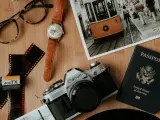 Paszport USA, aparat Canon, klisza, zegarek i okulary na drewnianym tle. Kto wydaje paszport? Rząd USA.