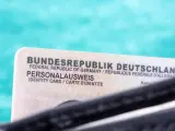 Niemiecki dowód osobisty (Personalausweis) na tle turkusowym.