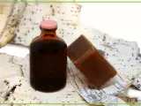 Brązowa buteleczka z płynem i kostka mydła na tle kory brzozowej. To naturalne produkty, a dziegieć co to? To właśnie taki ciemny, aromatyczny produkt.