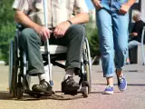 Osoba na wózku inwalidzkim z laską obok idącej osoby. Ulga na śmieci dla niepełnosprawnych to ważny temat.