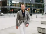 Elegancki mężczyzna w szarej marynarce w kratę i białych spodniach. Idealne połączenie, jeśli zastanawiasz się, jakie spodnie do szarej marynarki pasują.