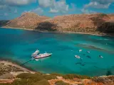 Wycieczka na Santorini z Krety: statki cumują w turkusowej zatoce, otoczonej skalistymi wzgórzami.