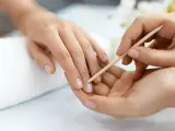 Delikatne dłonie poddawane zabiegowi manicure biologiczny. Skórki są starannie odsuwane patyczkiem, przygotowując paznokcie do dalszej pielęgnacji.