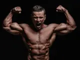 Mężczyzna z wyrzeźbionymi mięśniami napina bicepsy, krzycząc z wysiłku. Jego sylwetka sugeruje intensywny trening, być może z użyciem clenbuterolu.