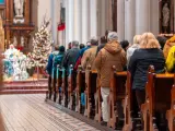 Ludzie siedzą w kościele przy choince. Czy w drugi dzień świąt trzeba iść do kościoła?