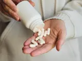 Dłonie wysypują białe kapsułki z butelki na suplement diety GABA.