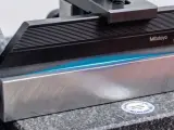 Precyzyjne pomiary 3D z użyciem wzorców Mitutoyo. Błękitne światło uwydatnia idealnie płaskie powierzchnie.