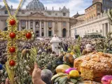 A jeweled cross, palm branches, and Easter treats in front of a crowd gathered for Holy Week in Italy.