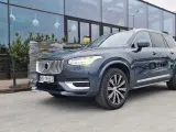 Elegancki, ciemnoszary Volvo XC90 T8 Recharge z polskimi tablicami rejestracyjnymi stoi przed nowoczesnym budynkiem z dużymi oknami.