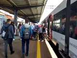 Ludzie czekają na pociąg na stacji w Lęborku. W tle widać budynek dworca i peron.
