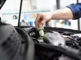 Ręka mechanika dokręca korek zbiorniczka płynu hamulcowego. Czas na badanie techniczne po terminie, by uniknąć problemów.