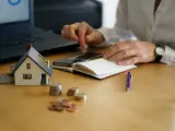 Osoba liczy pieniądze przy makiecie domu, zastanawiając się, ile wynosi czynsz za mieszkanie w bloku.