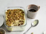 Un delizioso tiramisù al pistacchio, cosparso di granella verde, pronto per essere gustato con un caffè.