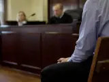 Osoba siedzi w ławie sądowej, czekając na decyzję w sprawie zgodnej z art. 37a. Sąd obraduje.