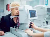 Starsza pani bada wzrok. Lekarz ustawia aparat, by zmierzyć perymetr pola widzenia.