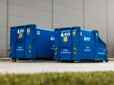 Dwa niebieskie kontenery BYS Recykling stoją przed budynkiem. Dowiedz się, ile kosztuje tona gruzu betonowego i jak go zamówić.
