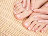Dłonie i stopy z perfekcyjnym pedicure french na bambusowym tle.