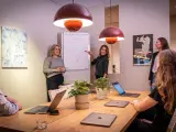Ett team diskuterar strategier vid ett konferensbord med flera laptops. En kvinna pekar på en trattmodell på en whiteboard. Ups datorn är en del av deras effektiva arbetsflöde.