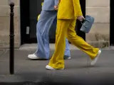 Un outfit tailleur con sneakers, giallo brillante e azzurro polvere, camminano sul marciapiede.