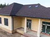 Nowy dom z dachem pokrytym ciemnymi łupkami bitumicznymi, z widocznymi oknami dachowymi i żółtą cegłą elewacyjną.