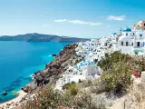 Vue panoramique de Santorin, Grèce, avec des maisons blanches et des dômes bleus surplombant la mer Égée.