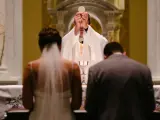 Para młoda klęczy przed ołtarzem, kapłan podnosi hostię. Modlitwa za żonę w tym ważnym dniu.