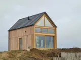 Nowy dom modułowy na wzgórzu, z drewnianą elewacją i dużymi oknami. Czy jego wady są widoczne?