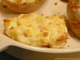En närbild på en krämig, osttäckt bakad potatis fylld med baconbitar.