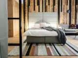 Przytulny pokój w hotelu butikowym. Co to? To miejsce z drewnianą ścianą, wygodnym łóżkiem i stylowym dywanem.
