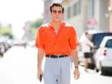 Hombre con camisa naranja estampada y pantalones grises, luciendo un elegante french tuck.