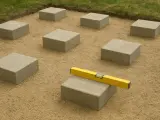 Układanie betonowych bloków pod przyszły taras. Poziomica na jednym z nich zapewnia równość.