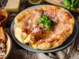 Langosz co to? Puszysty, złocisty placek z sosem pomidorowym i parmezanem, ozdobiony listkiem bazylii.