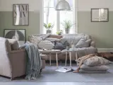 Vardagsrum i svensk stil med bekväm soffa, fåtölj och en sovande hund. Vårljus strömmar in genom fönstret och skapar en mysig atmosfär.