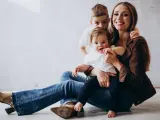 Szczęśliwa mama z dwójką dzieci, maluszkiem na rękach i starszym synkiem za plecami. Idealny urlop na dziecko.