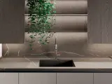 Nowoczesna kuchnia z blatem i płytą backsplash z kamienia, przypominającego marmur. Wisząca zieleń dodaje życia.