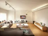 Iluminar un salón moderno con luces de riel y lámpara de arco. Sofás grises, mesa de centro blanca y mueble de TV.