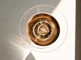 Szklanka z różowym, musującym winem, które wygląda jak tanie wino, ale jest podane w elegancki sposób. Bąbelki unoszą się ku górze.
