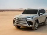 Srebrny Lexus LX 600 przemierza pustynię, zostawiając ślady na piasku.